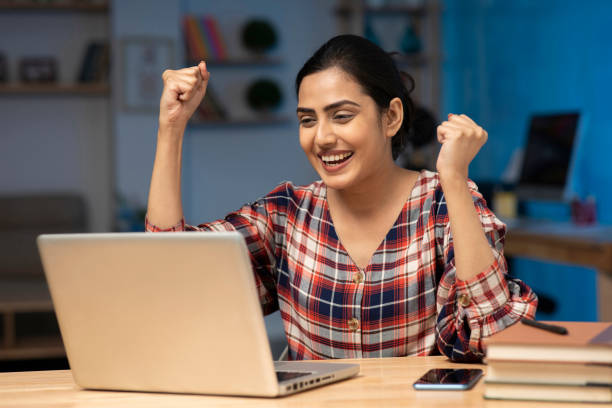 Happy woman studying for PTE Exam with determination on laptop